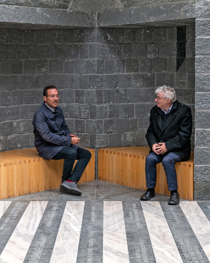 Two men in conversation in a stone building